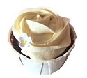 Red Velvet cupcake topped with cream cheese frosting and is further decorated with a mini white flower made of icing at the side